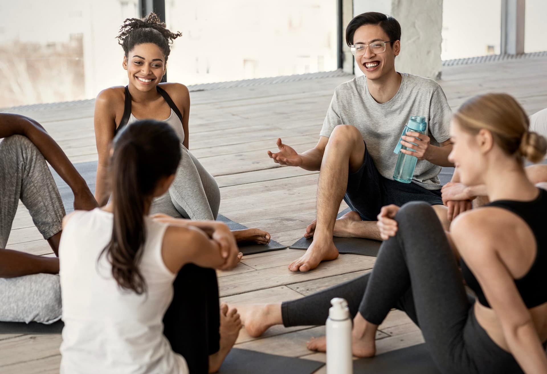 Group of multiracial young people communicating before yoga class in studio