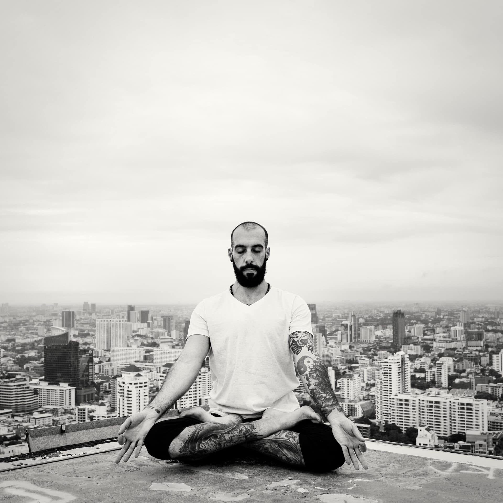 Man practicing yoga on the rooftop and cityscape background
